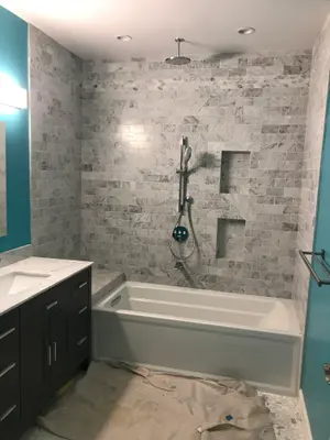 Bathroom remodel showing marble tiling surrounding tub